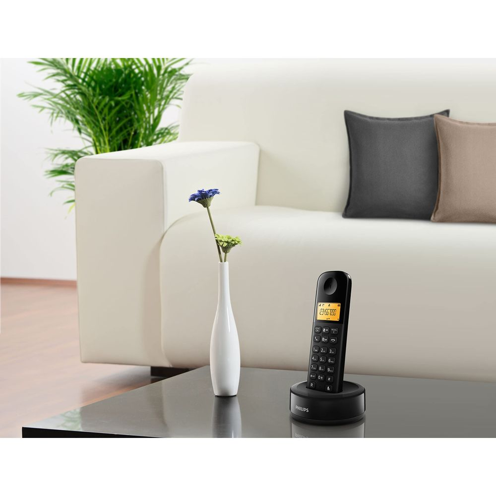 Un téléphone sans fil repose sur une table devant un canapé blanc.