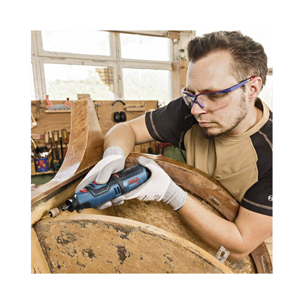 Hombre con gafas de seguridad usa herramienta Bosch azul en objeto de madera.