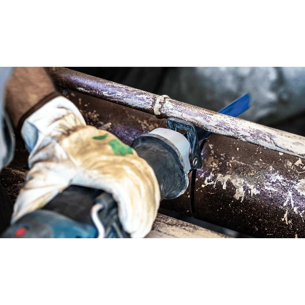 Narzędzie tnące zardzewiałą rurę. Ramię w rękawicy trzyma narzędzie.