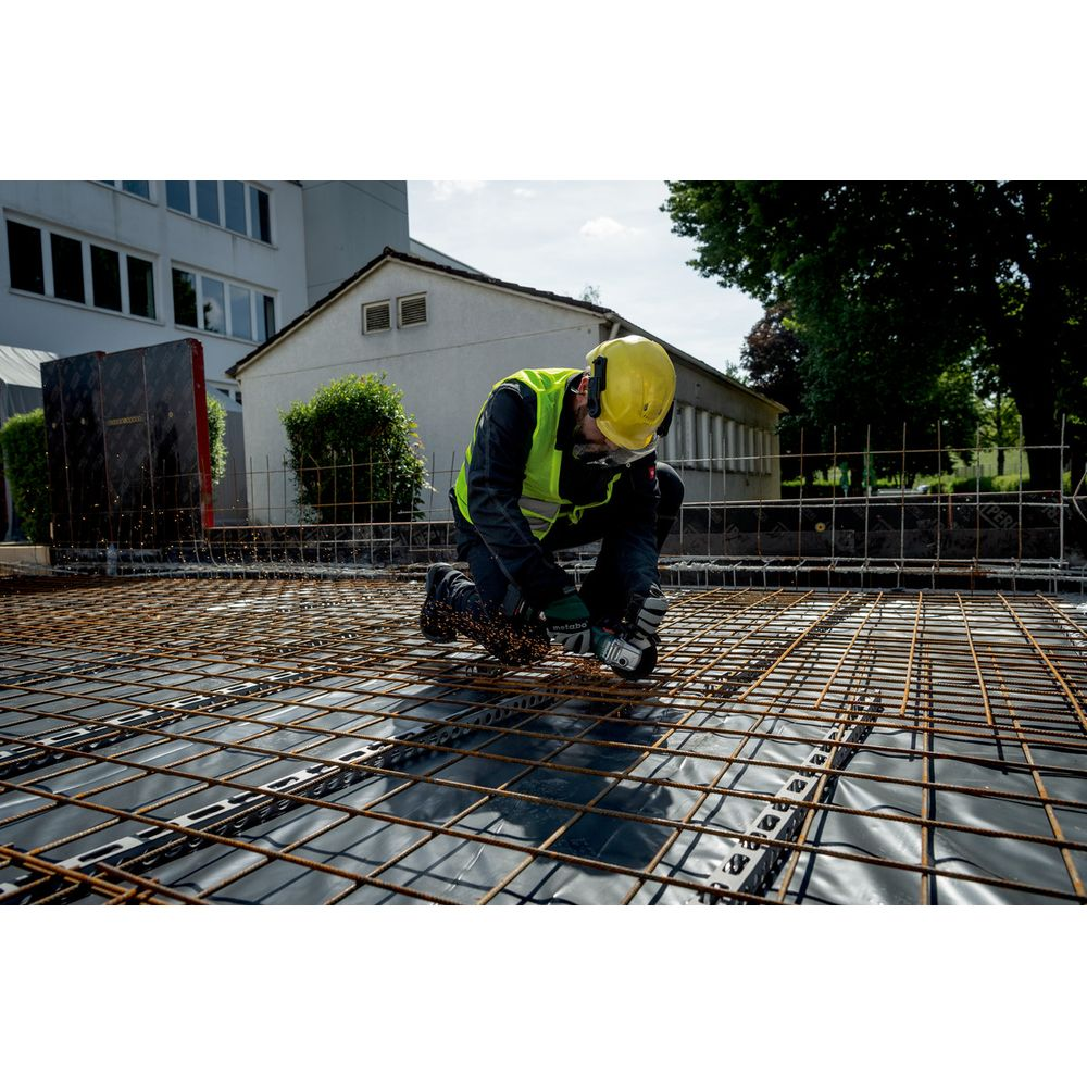 Ouvrier utilise meuleuse d'angle sur chantier avec armatures.