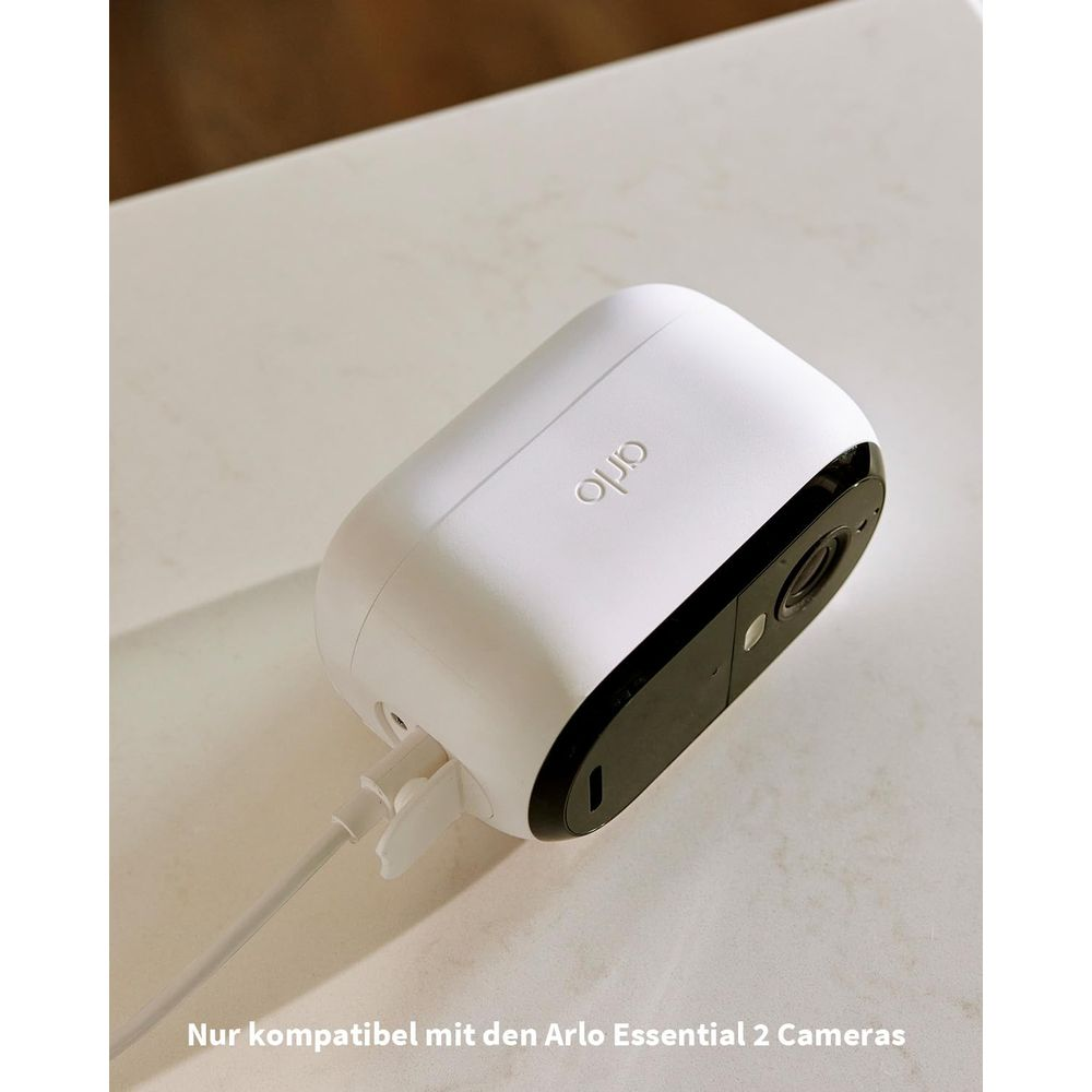 Telecamera Arlo bianca con lente nera, in carica via USB, su tavolo.