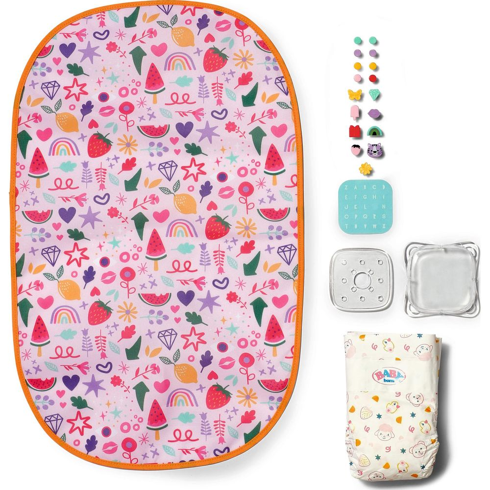 Mata do przewijjak Baby Born z owocami, sercami i gwiazdami, obok akcesoriów takich jak naklejki, siatka ABC i pielucha.