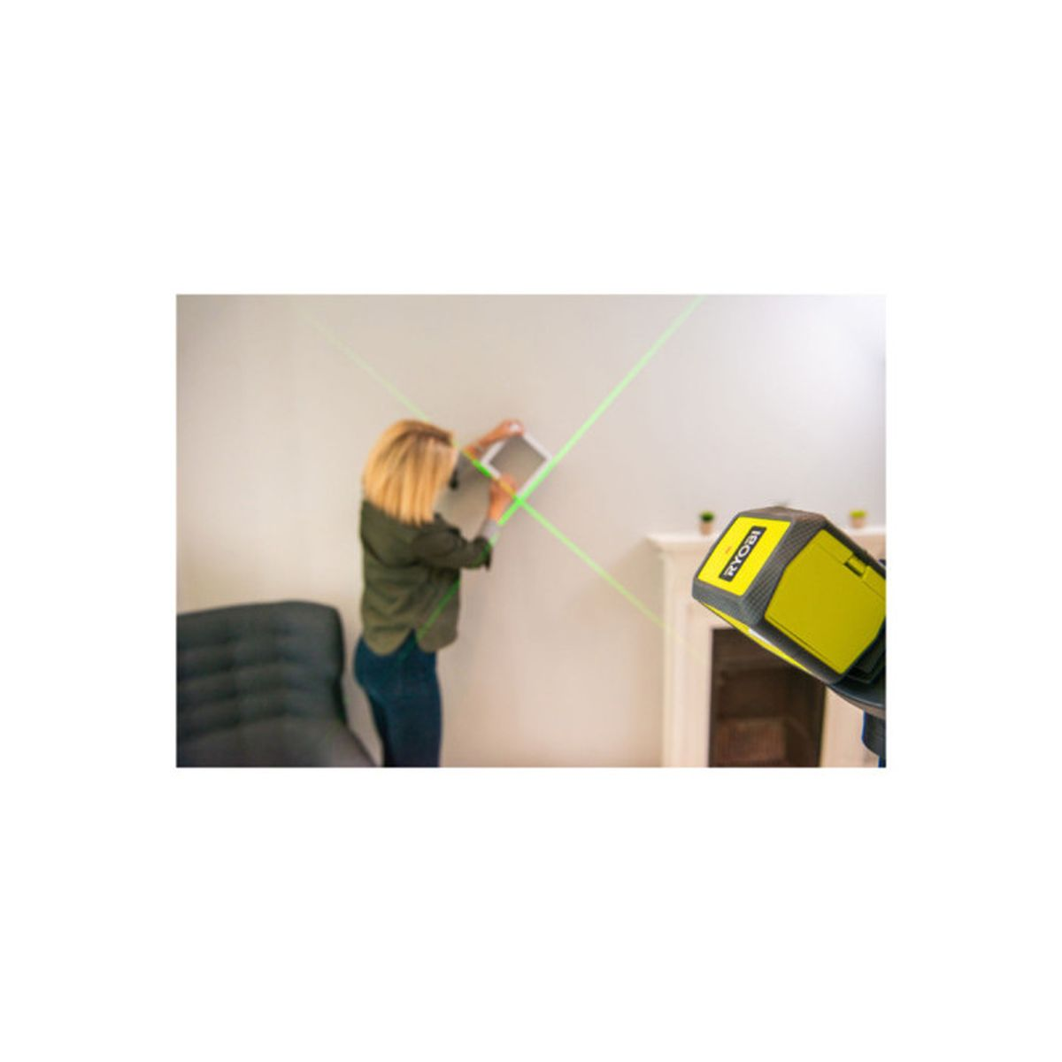 Eine Frau richtet einen grünen Laserstrahl an der Wand aus, um etwas zu montieren.