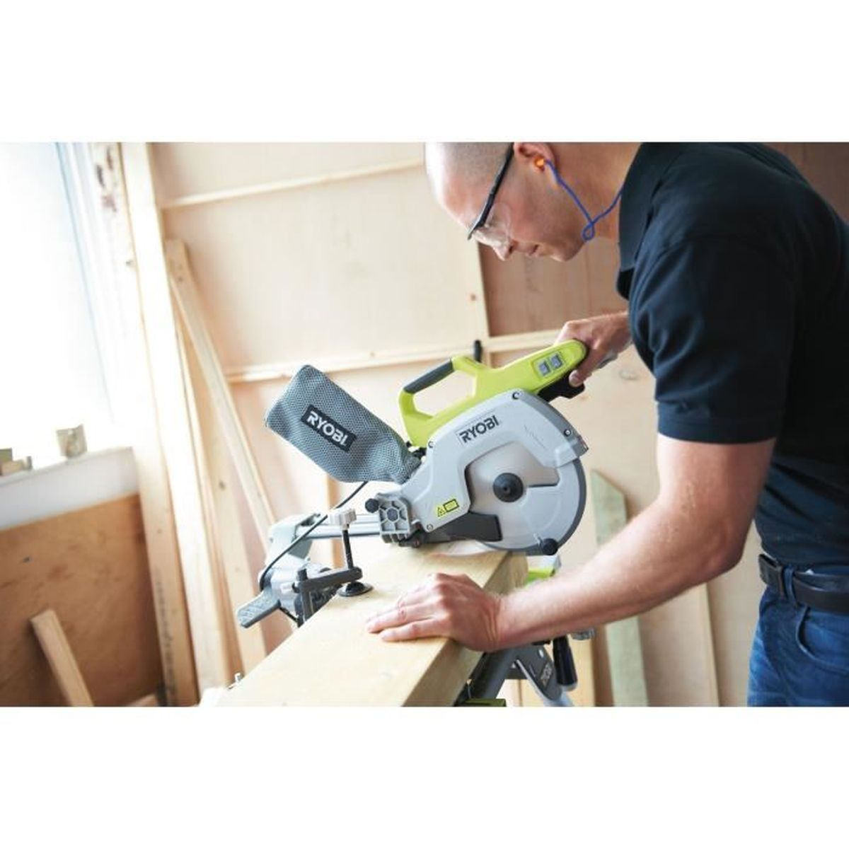 Mann benutzt eine Kapp- und Gehrungssäge, um Holz zu schneiden. Er trägt Schutzbrille und Gehörschutz.
