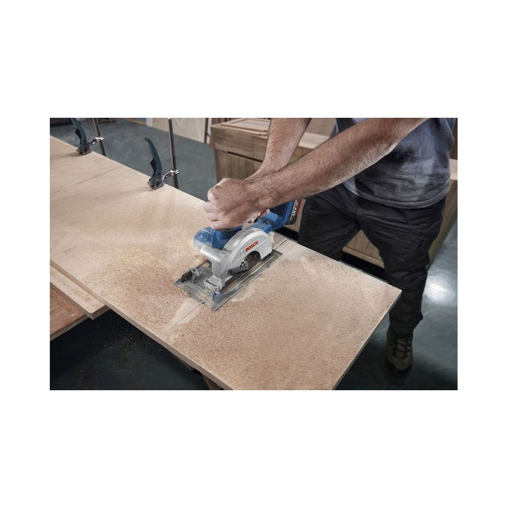 Mann schneidet Holz mit Kreissäge. Staub wird aufgewirbelt.