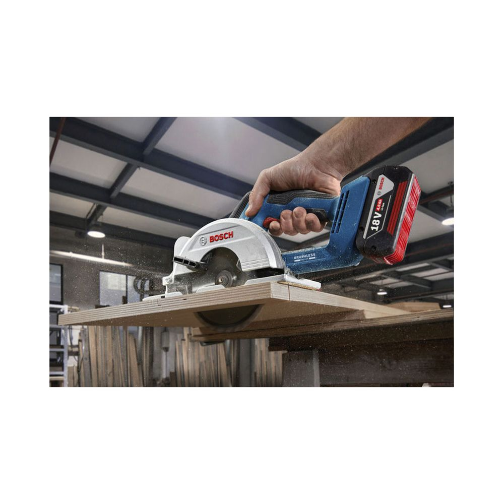 Hand hält Bosch-Kreissäge, die Holz schneidet. Staub fliegt auf.