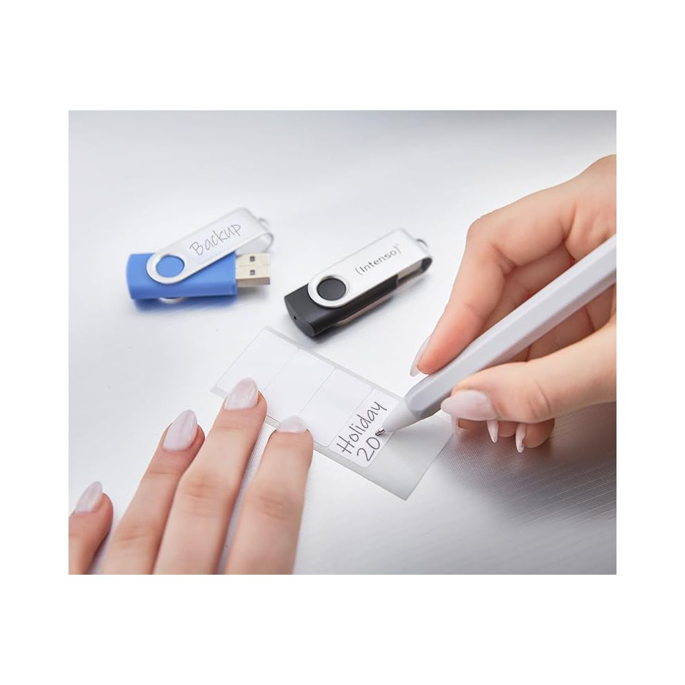 Ręka etykietuje karteczkę samoprzylepną, obok leżą dwa pendrive'y.
