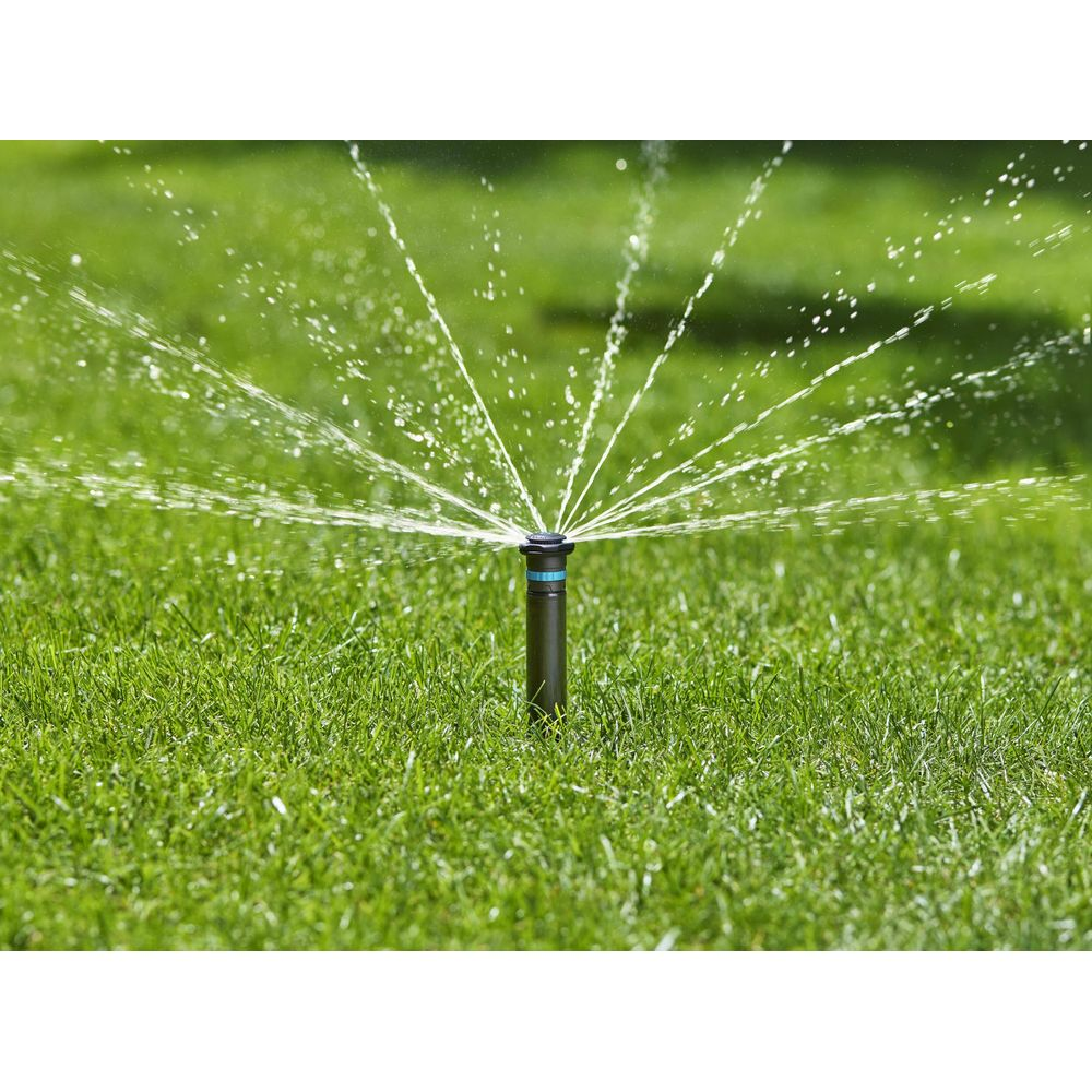 Un irrigatore spruzza acqua su un prato verde.