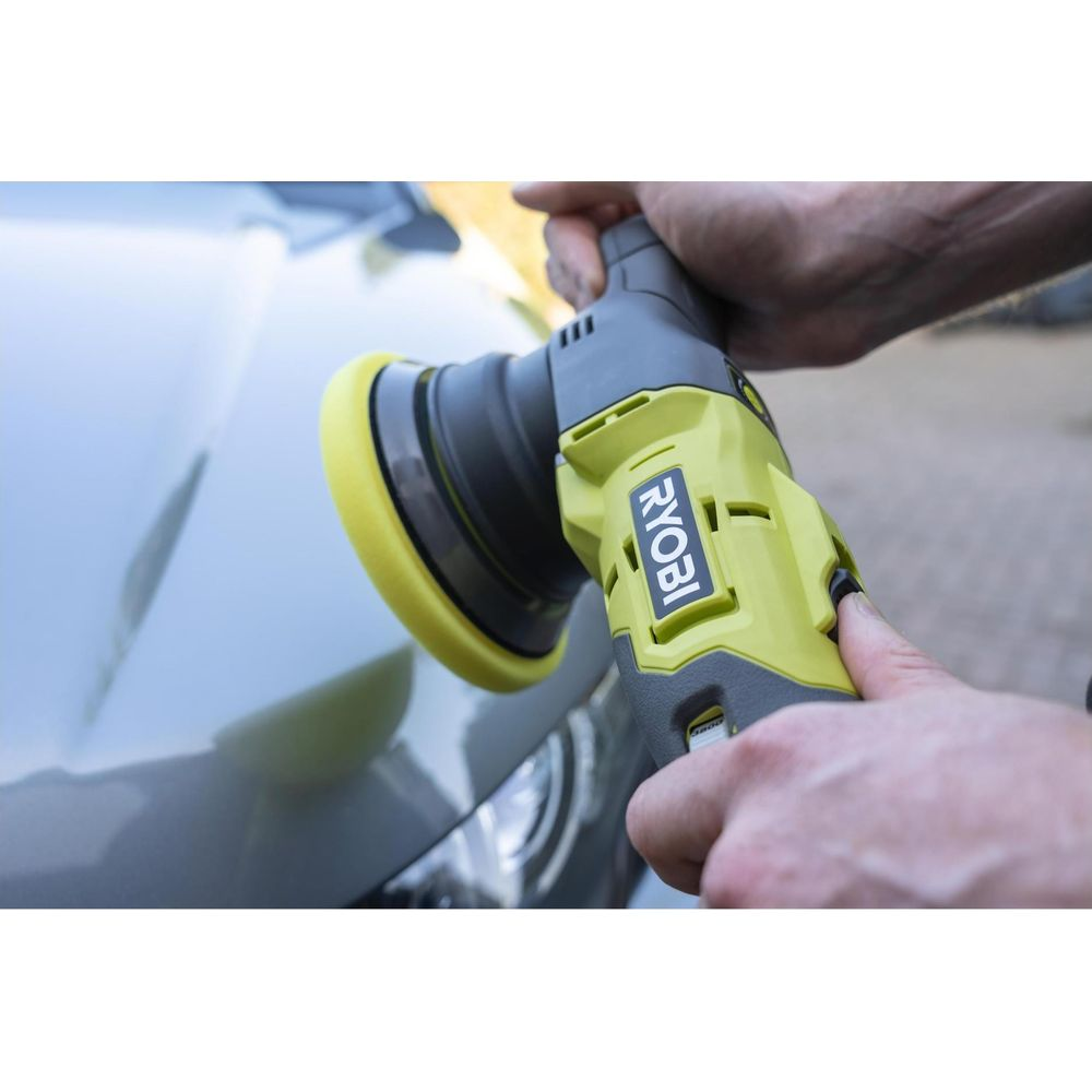 Detailer poliert Auto mit gelbem Schwingschleifer. Grau glänzende Oberfläche.