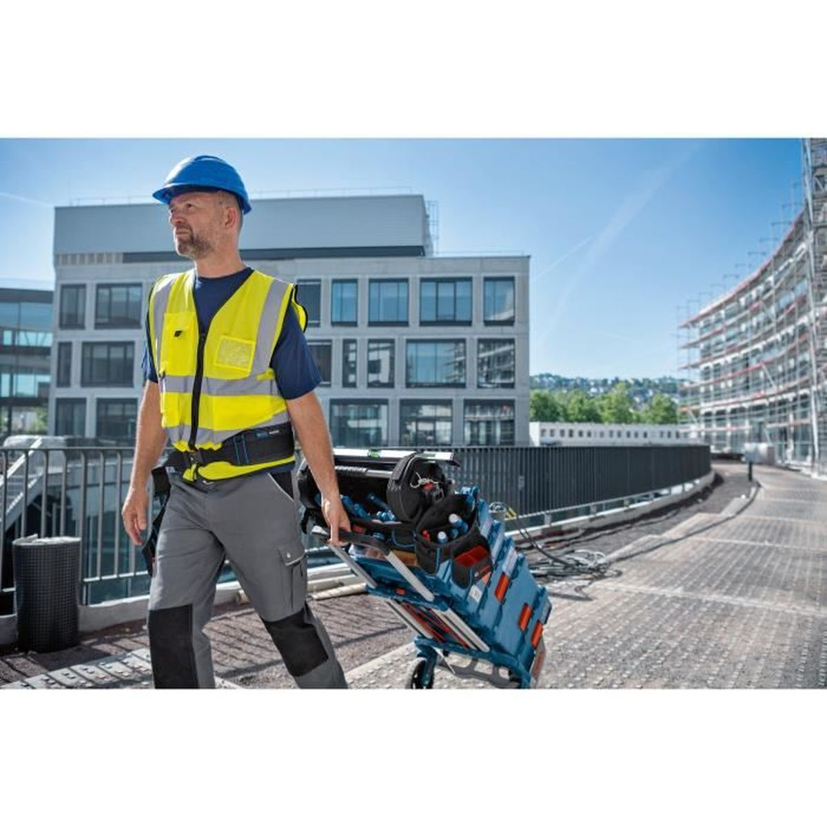 Ein Mann in Arbeitskleidung schiebt eine Werkzeugkiste auf Rädern.