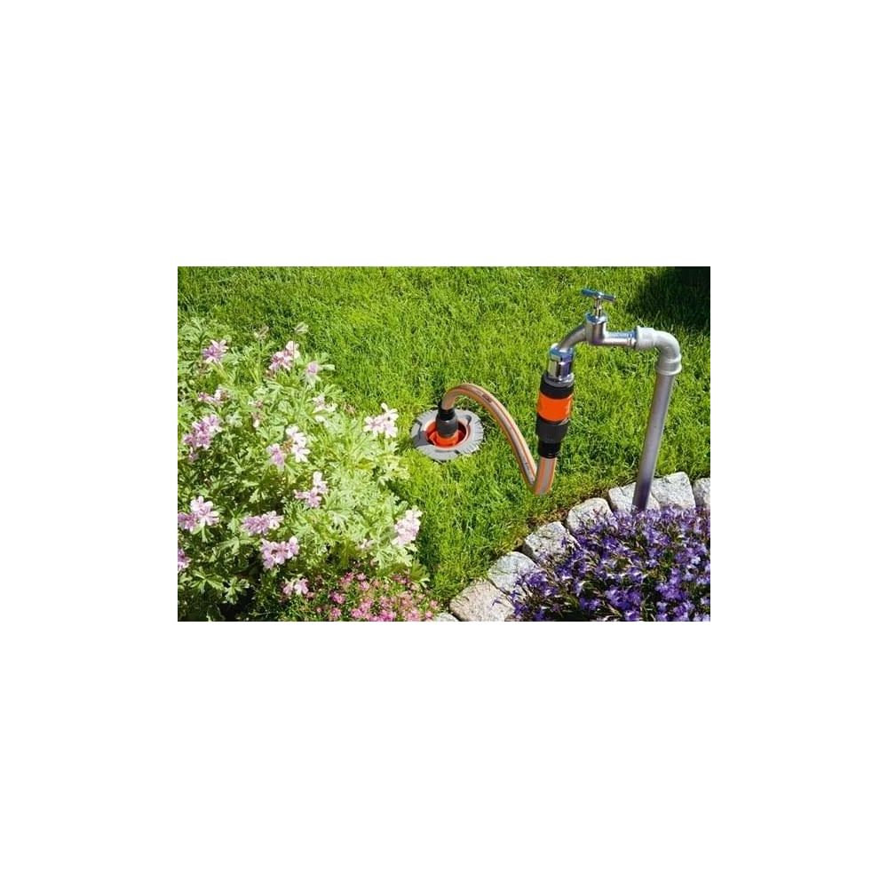 Gartenschlauch mit Wasserhahn und Blumenbeet.
