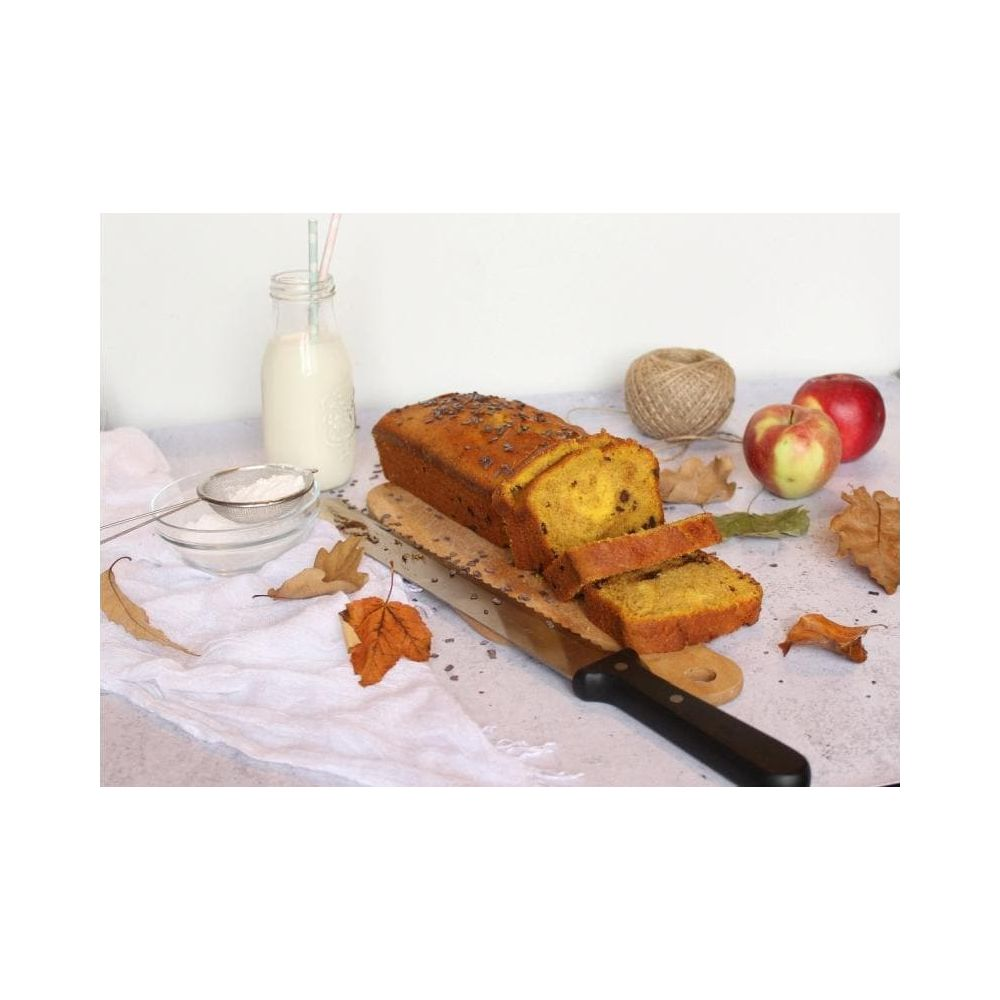 Ein geschnittener Kuchen mit Schokoladenstückchen, Äpfeln, Milch und Blättern.