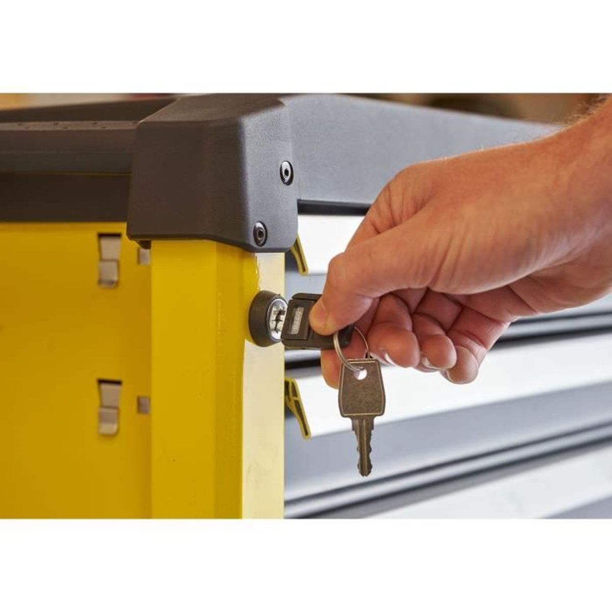 Una mano introduce una llave en la cerradura de un cajón amarillo.