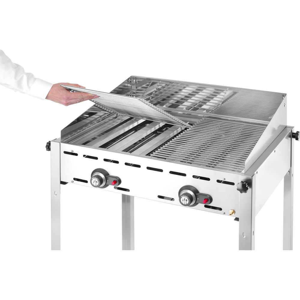 Una persona posiziona una griglia su un barbecue in acciaio inox con due manopole.
