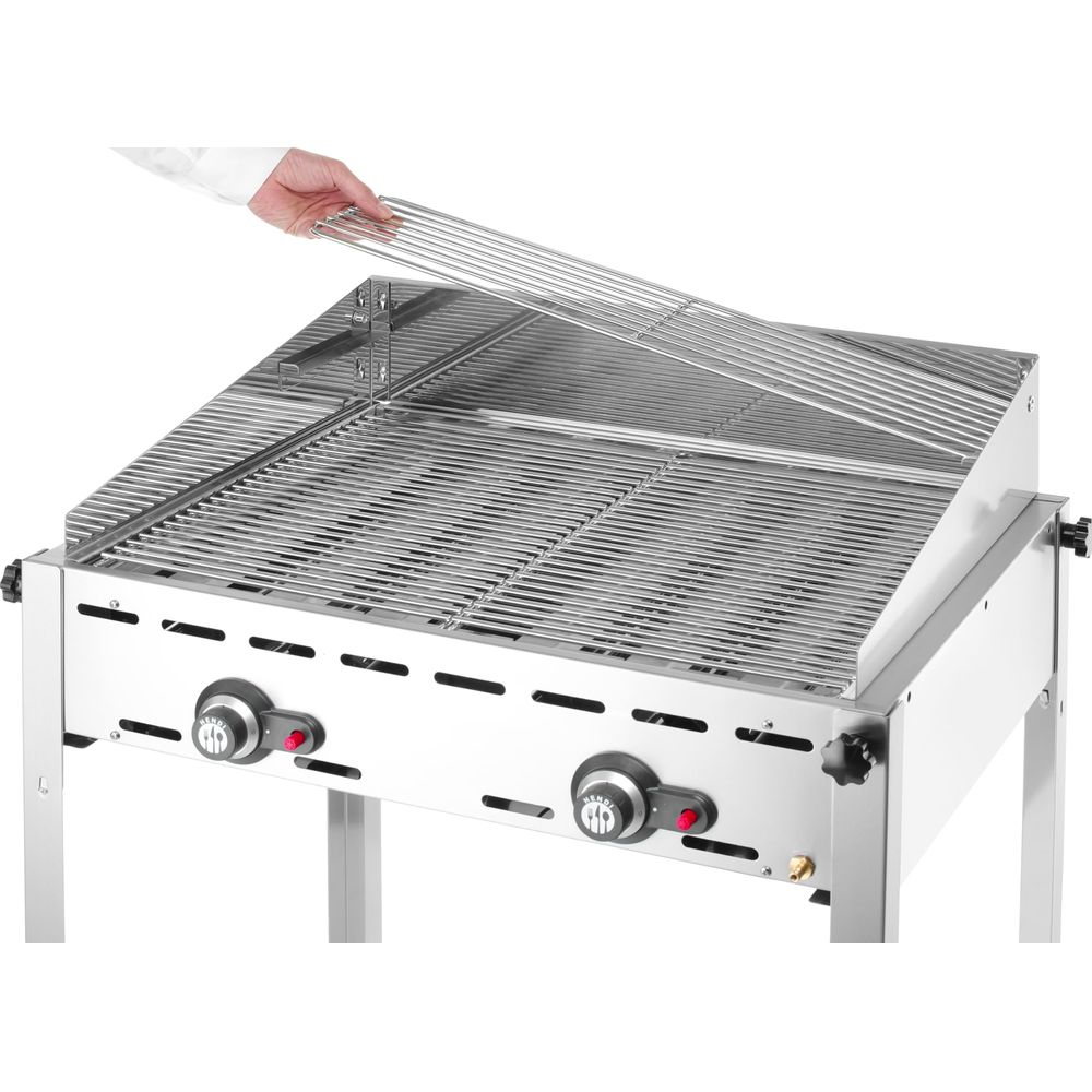 Una mano posiziona una griglia su un barbecue in acciaio inox con due manopole.