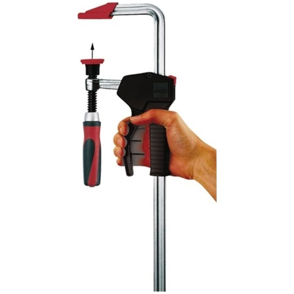 Dłoń trzyma zacisk z czerwonym uchwytem i srebrnym metalem.