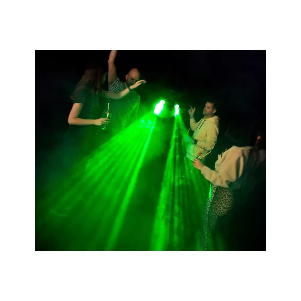Menschen tanzen im grünen Lichtkegel auf einer dunklen Party.
