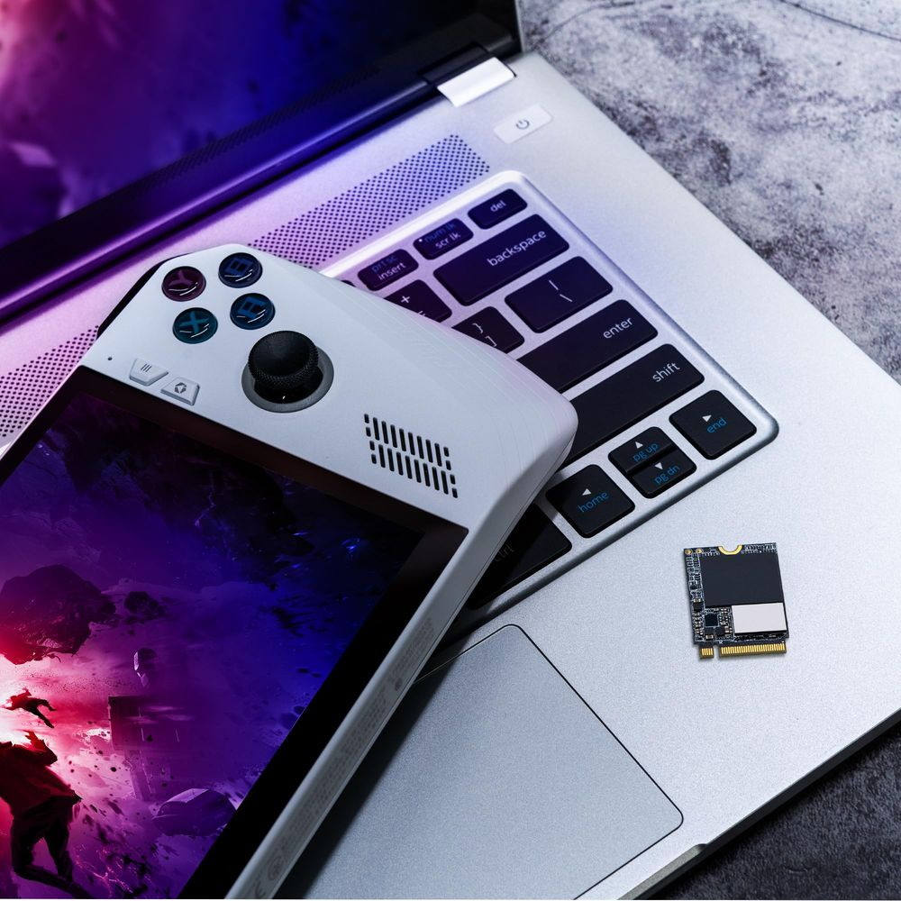 Białe urządzenie podręczne spoczywa na klawiaturze laptopa obok małego chipu pamięci.