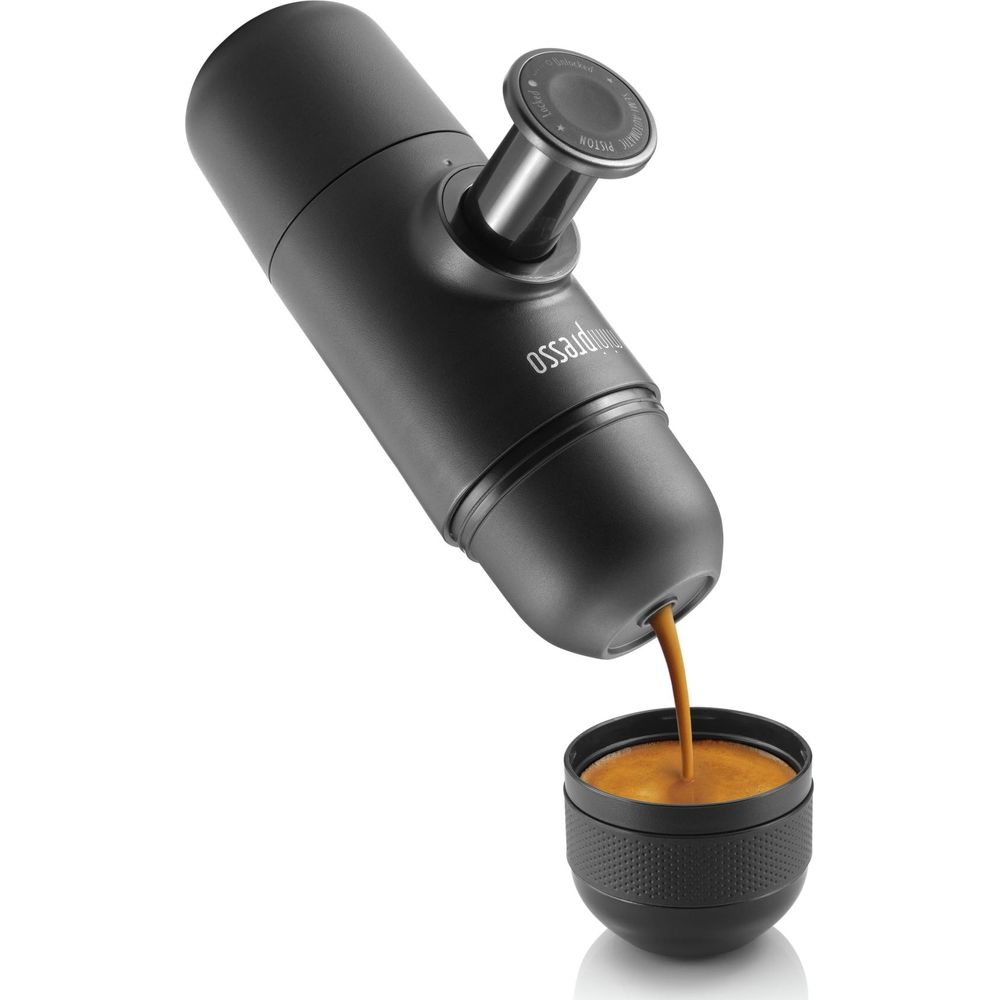 Ein schwarzer Espresso-Maker gießt Kaffee in eine kleine Tasse.