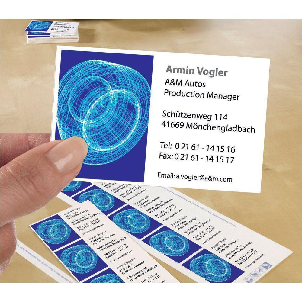 Eine Hand hält eine Visitenkarte mit blauem Muster. Mehrere Karten liegen daneben.