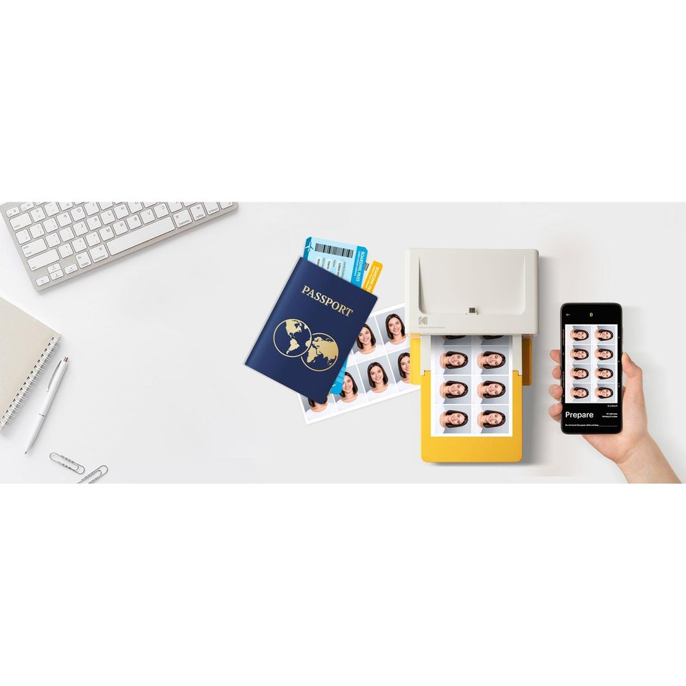Ein Drucker druckt Passfotos, daneben ein Smartphone, Reisepass und Tastatur.