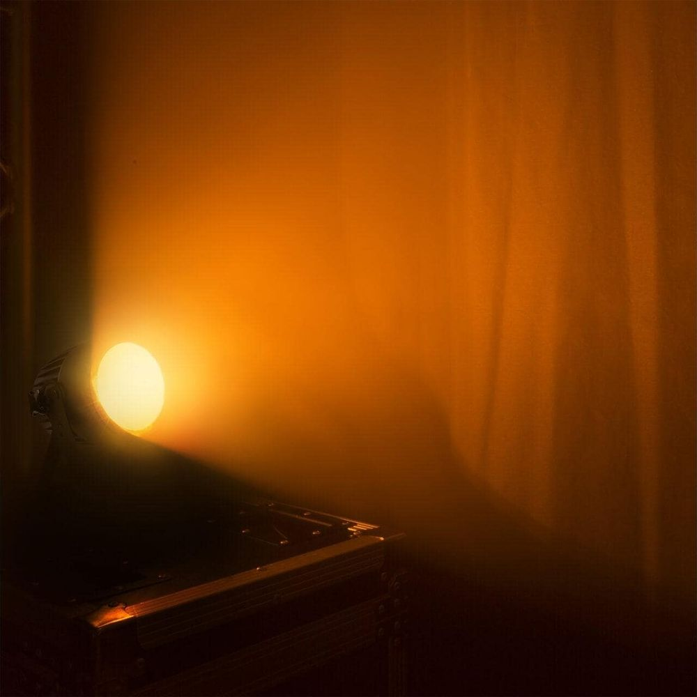 Un foco ilumina una pared con luz naranja.