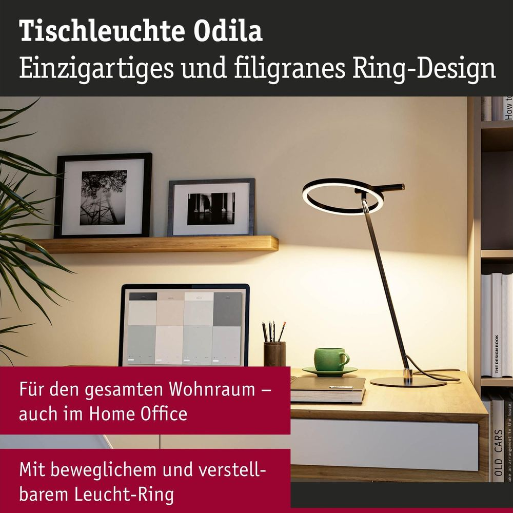 Nowoczesna lampa biurkowa w kształcie pierścienia na biurku z dekoracjami i książką.