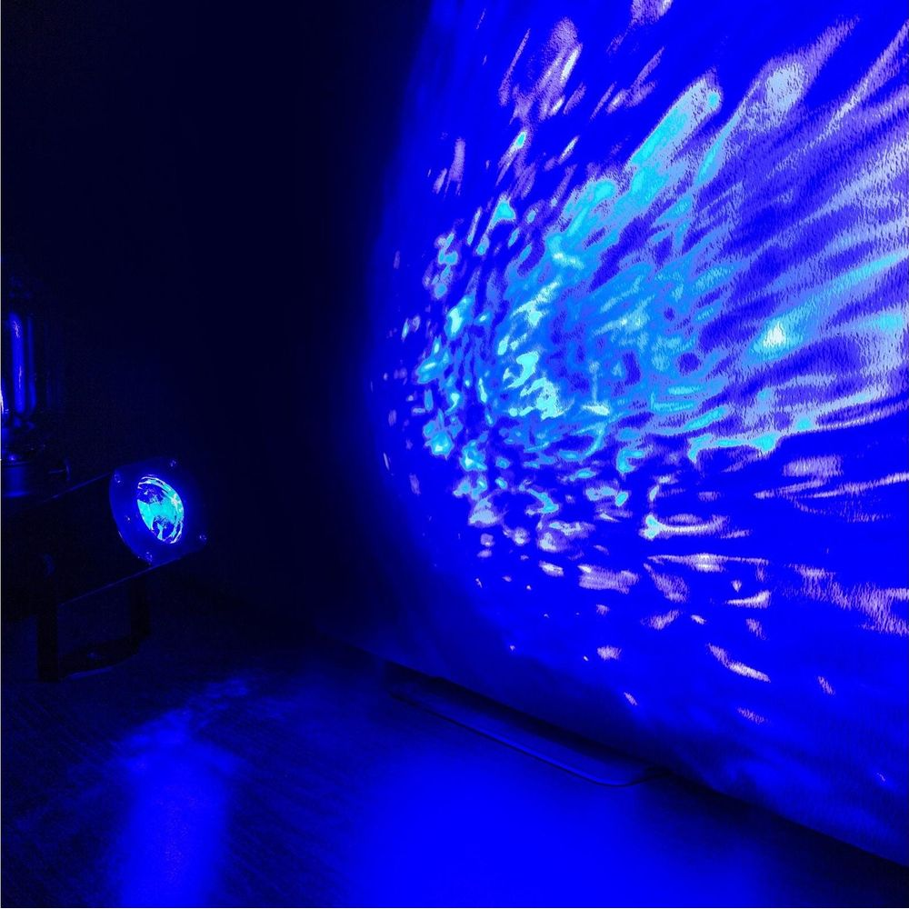 Un proyector azul proyecta patrones de olas en una pared.
