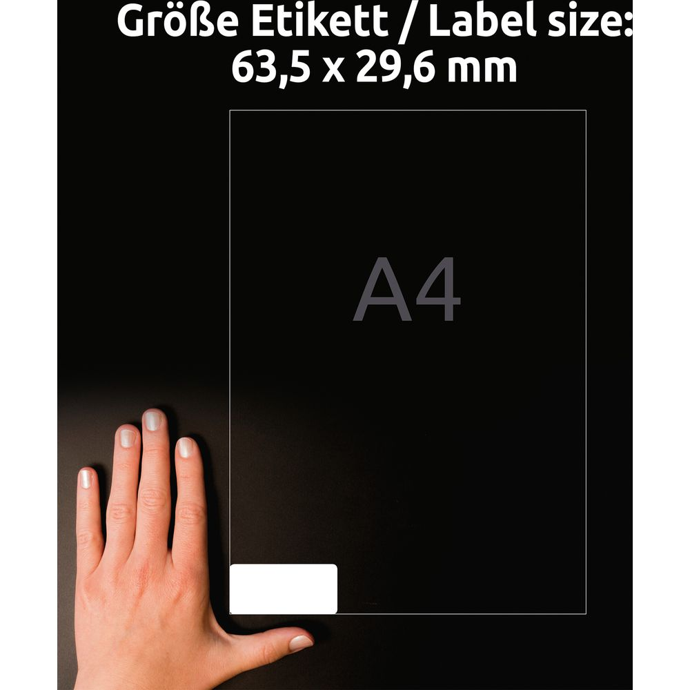 Eine Hand zeigt auf ein Blatt Papier der Größe A4 mit Etikettengröße 63,5 x 29,6 mm.