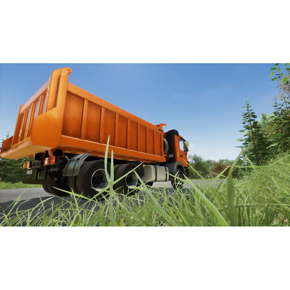 Ein orangefarbener Kipper fährt auf einer Straße, umgeben von Gras und Bäumen.
