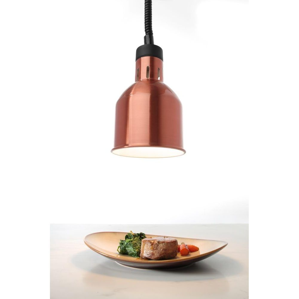 Un paralume in rame illumina una tenera bistecca con spinaci e carote su un piatto.