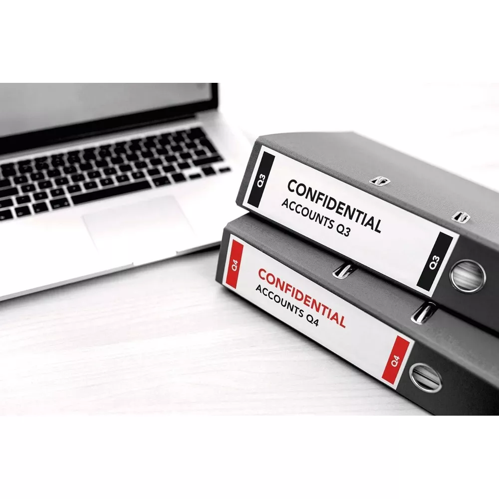 Dos carpetas con "CONFIDENTIAL ACCOUNTS Q3" y "CONFIDENTIAL ACCOUNTS Q4" junto a un portátil.