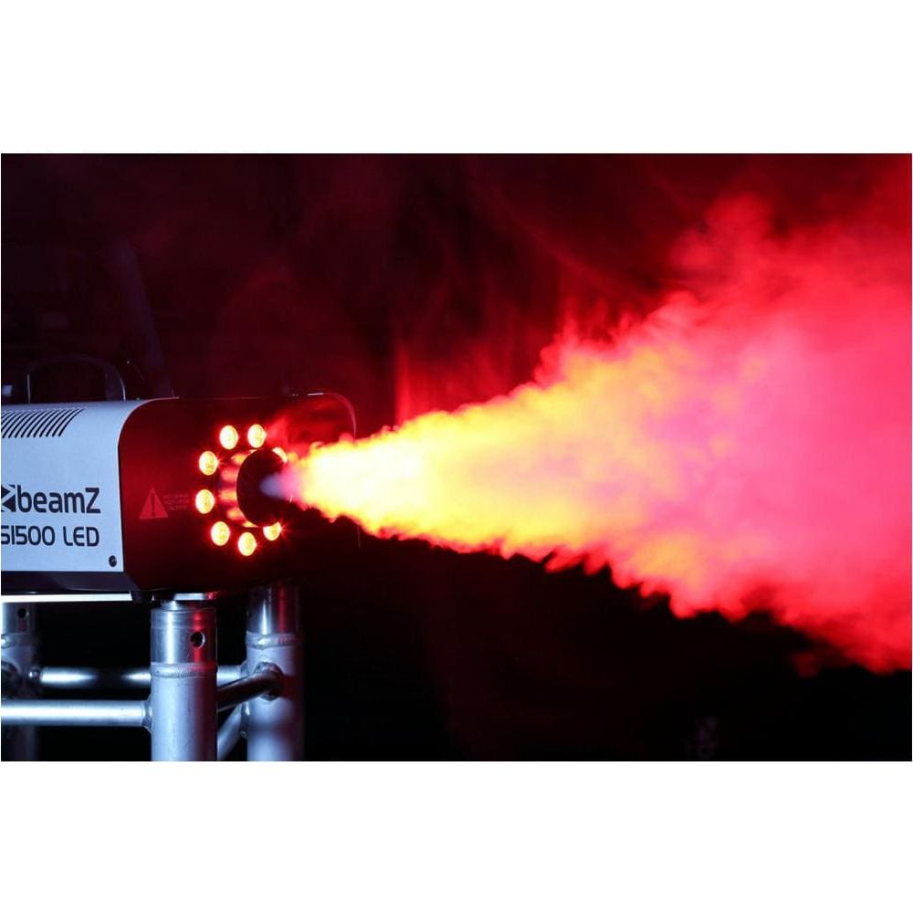 Una máquina de humo emite humo rojo y amarillo. Está montada en un soporte metálico.