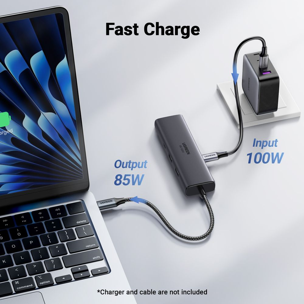 Laptop jest zasilany przez szary hub USB-C, podłączony do zasilacza.