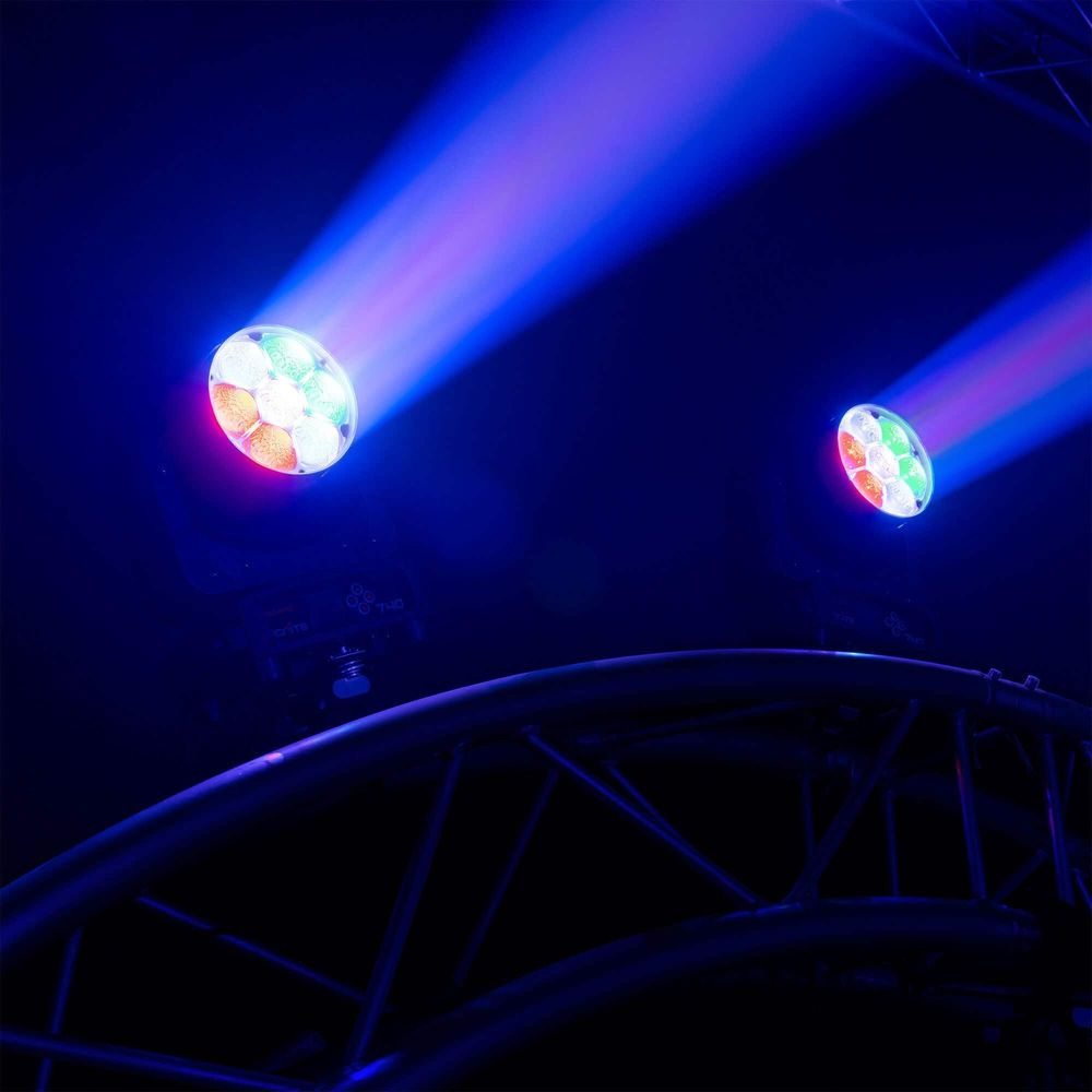 Dos luces de escenario de colores emiten haces azules y morados en la oscuridad.