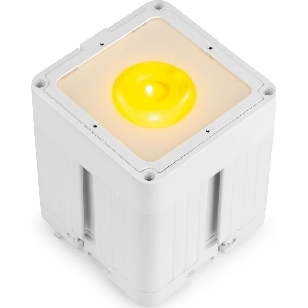 Un cubo blanco con una fuente de luz amarilla arriba.