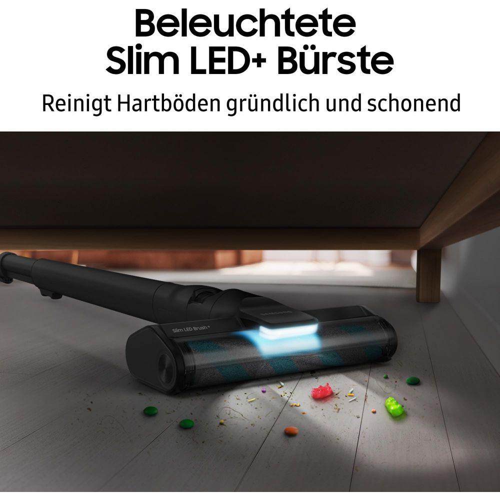Eine leuchtende Staubsaugerbürste reinigt Krümel vom Boden unter einem Möbelstück.