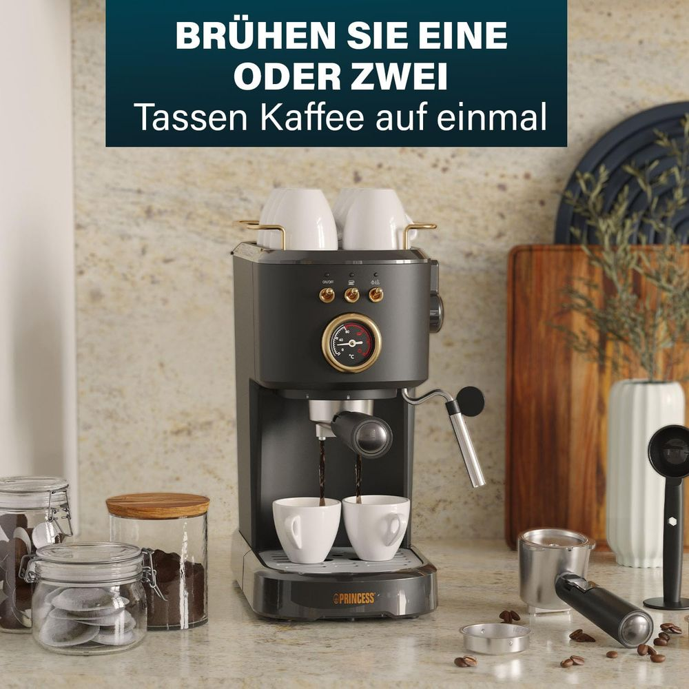 Czarny ekspres do kawy parzy kawę do dwóch białych filiżanek. Akcesoria i kapsułki z kawą obok.