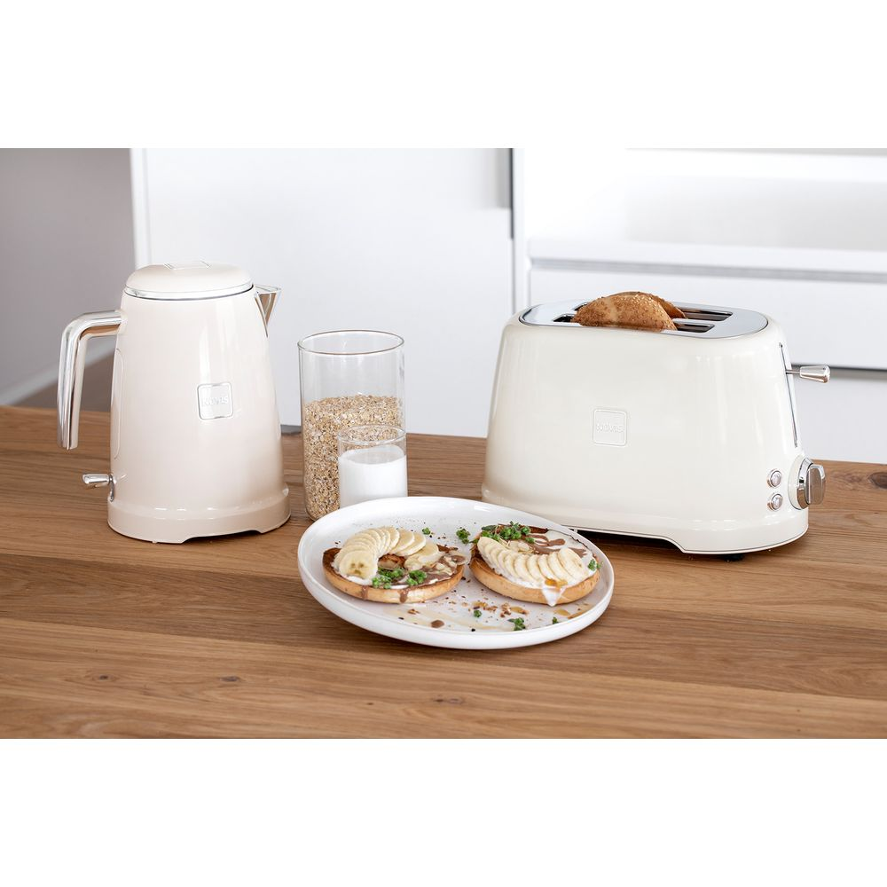 Ein cremefarbener Wasserkocher, Toaster, Müsli, Milch und Bananen-Bagels auf Holztisch.
