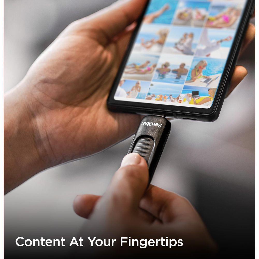 Dłoń trzyma smartfon podłączony do pendrive'a SanDisk. Na ekranie wyświetlane są zdjęcia z wakacji.