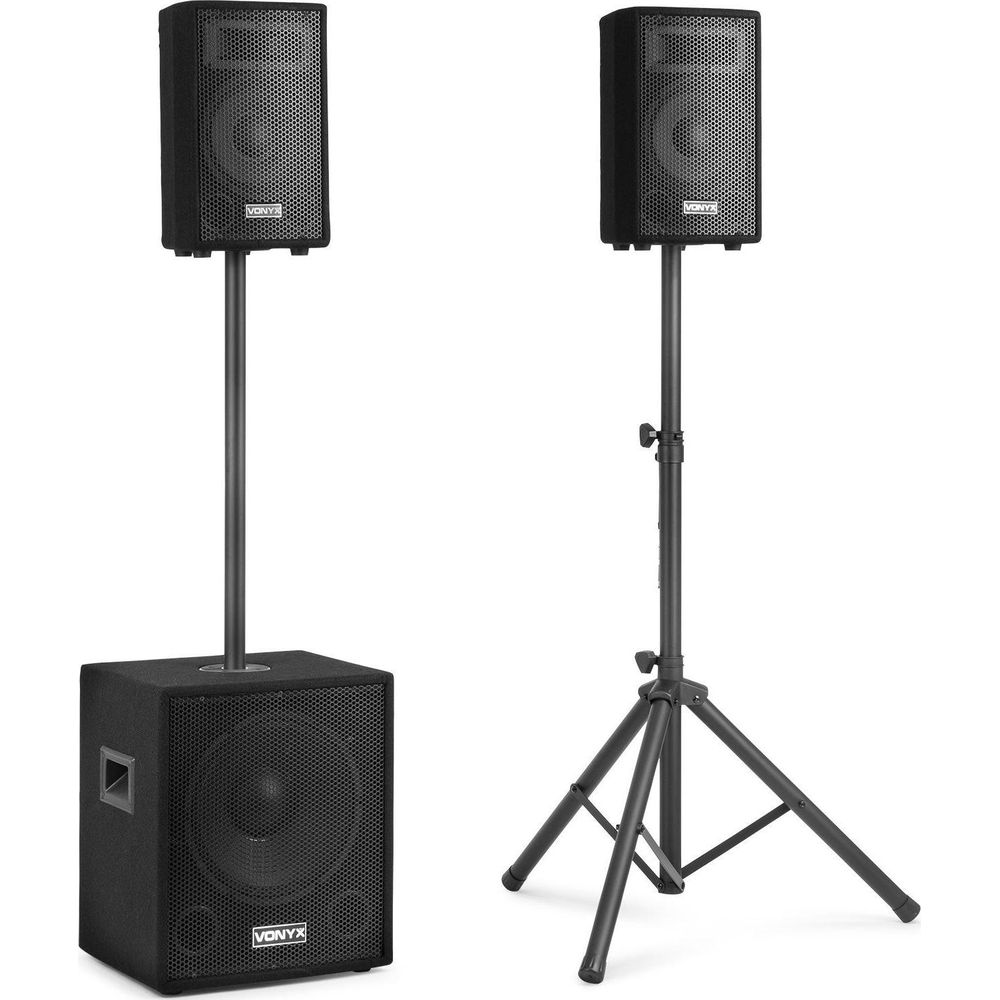 Deux enceintes noires sur pieds, un caisson de basses à gauche.