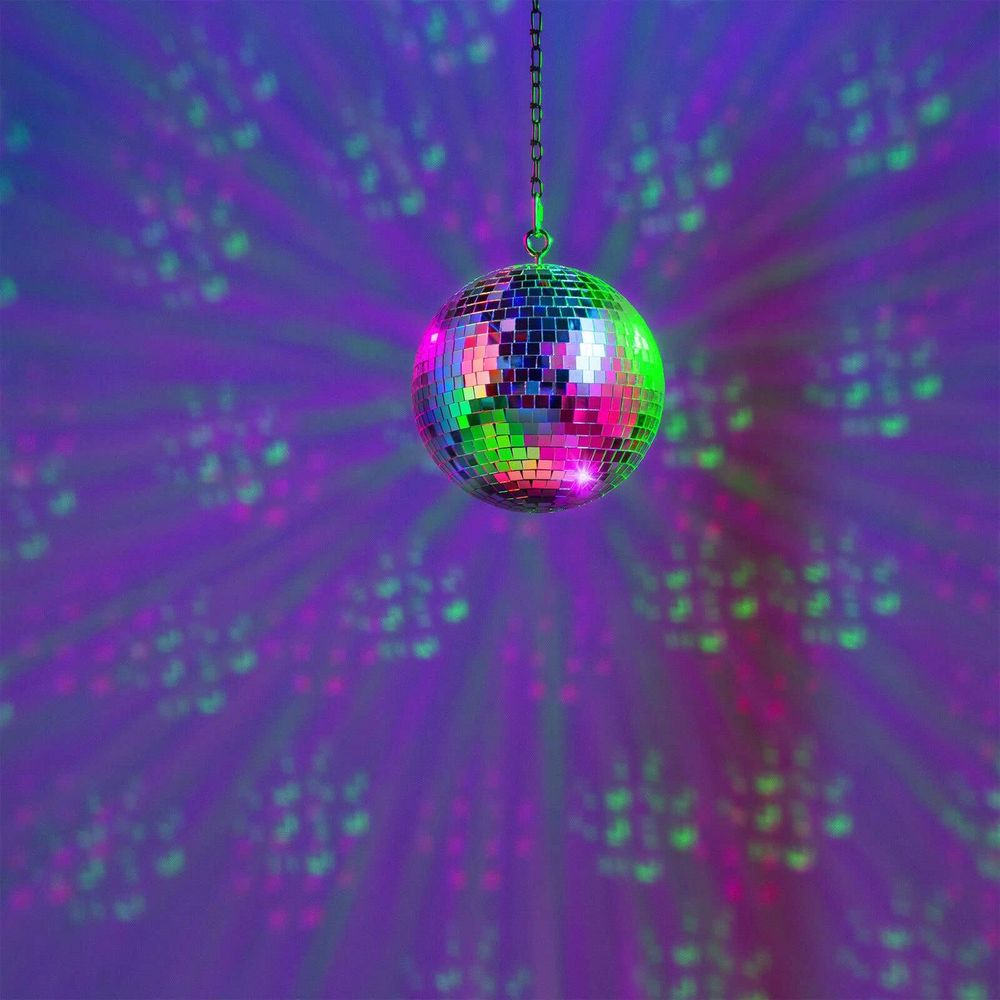 Una bola de discoteca cuelga de una cadena, proyectando luces de colores en una pared morada.