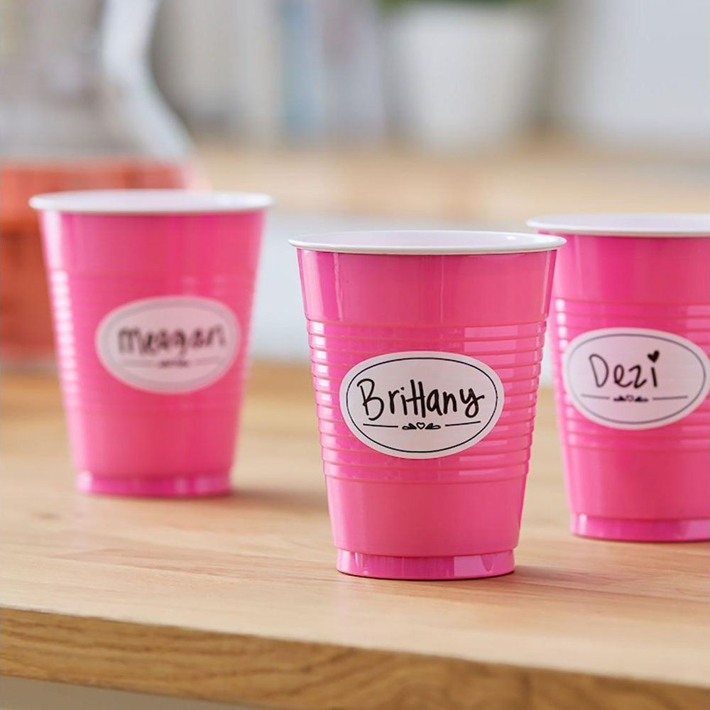 Drei pinke Becher mit Namen wie Brittany, Dezi und Meagan auf ovalen Etiketten.