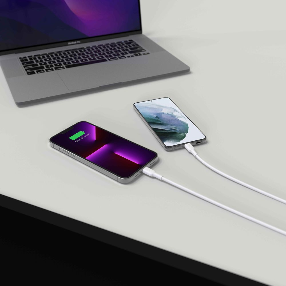 Un laptop carica due smartphone su una scrivania.