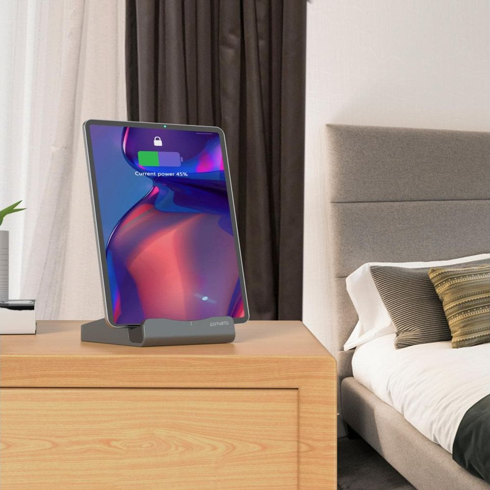 Un tablet si sta caricando su un comodino accanto a un letto.