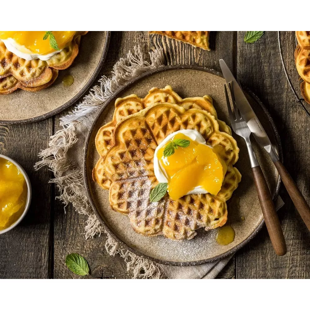 Gofry w kształcie serca ze śmietaną i plasterkami brzoskwini, posypane cukrem.