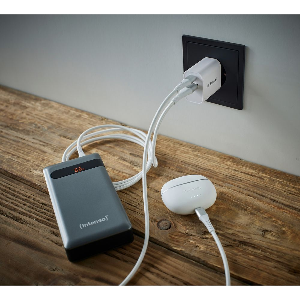 Power bank grigia e auricolari bianchi in carica dalla presa.