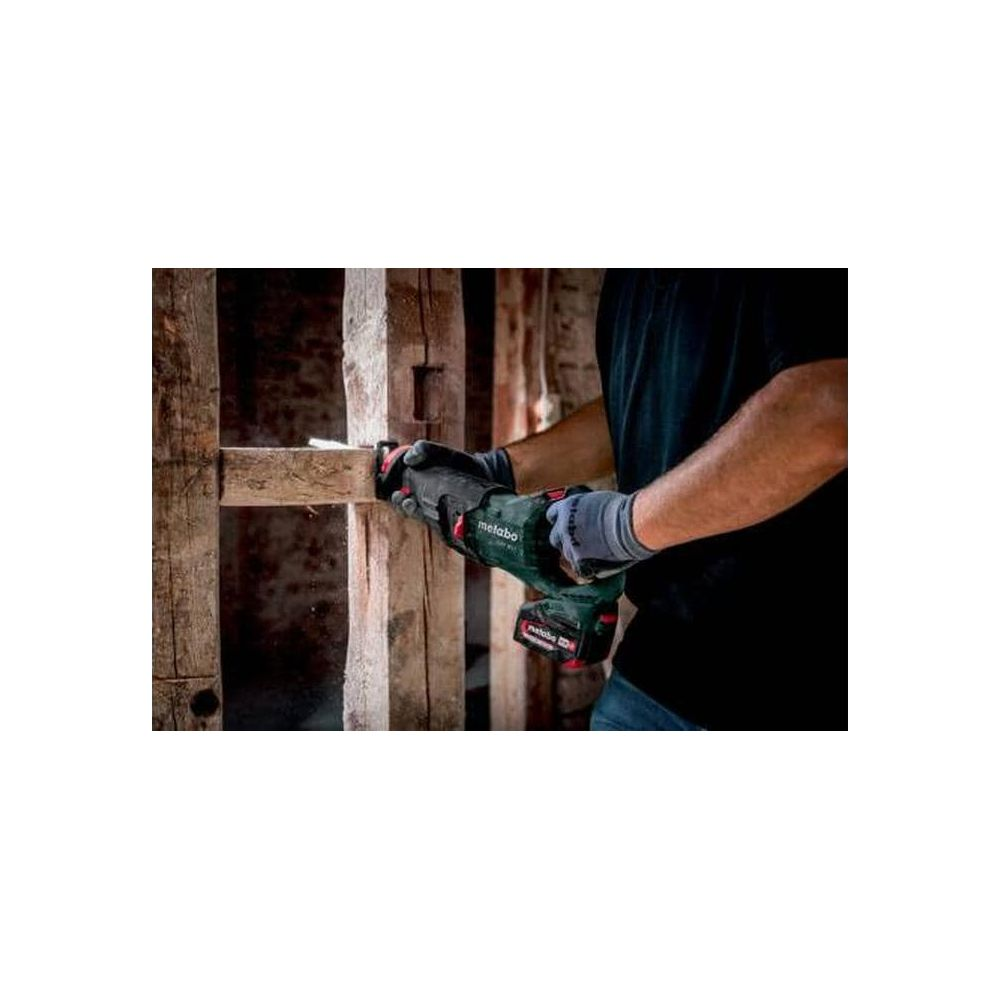 Mann mit Säge arbeitet an Holzkonstruktion. Dunkle Kleidung, Handschuhe.