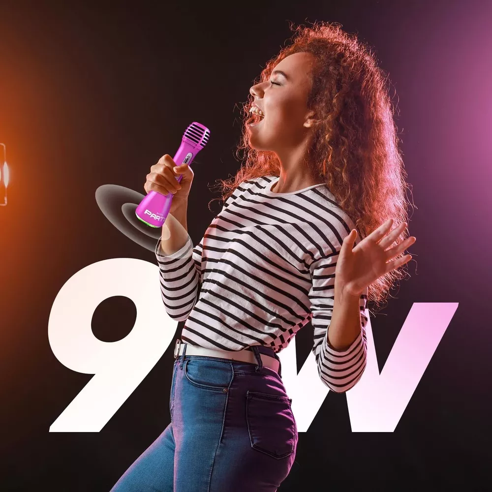 Giovane donna con capelli ricci canta in un microfono rosa, top a righe.