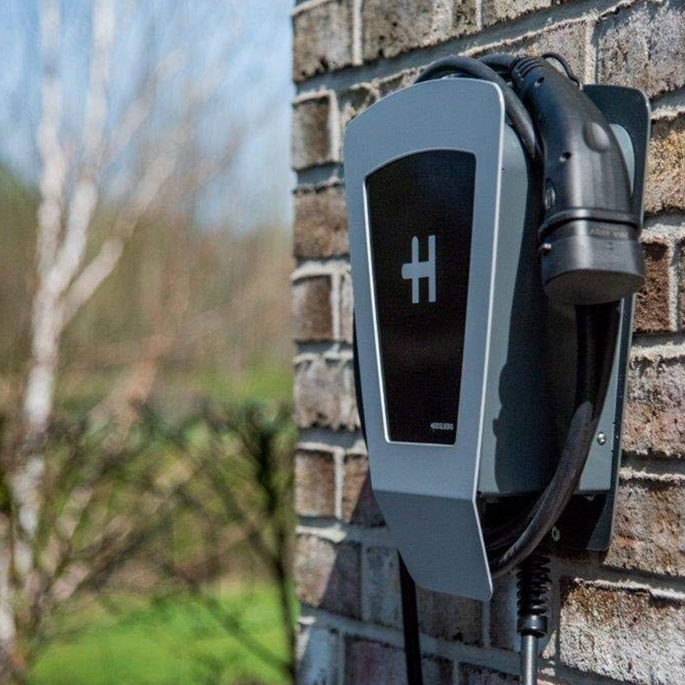 Ladestation für Elektroautos an einer Ziegelwand mit einem Kabel und Stecker.